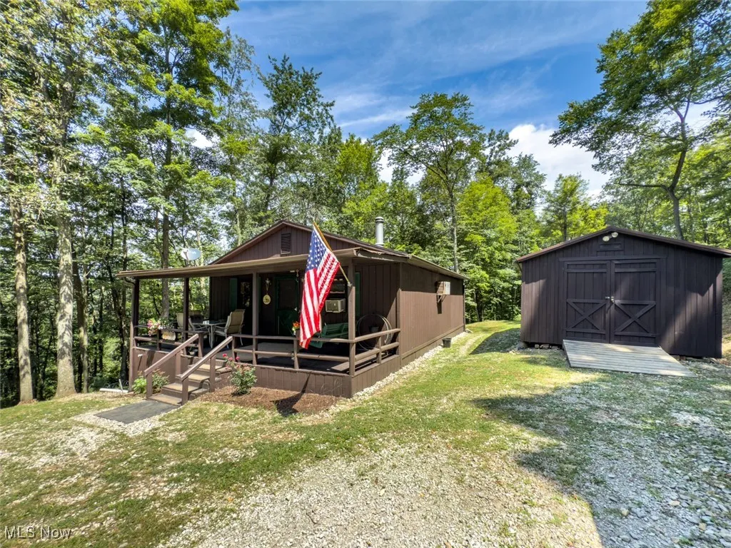 View of front facade featuring a front lawn, a storage shed, and covered porch