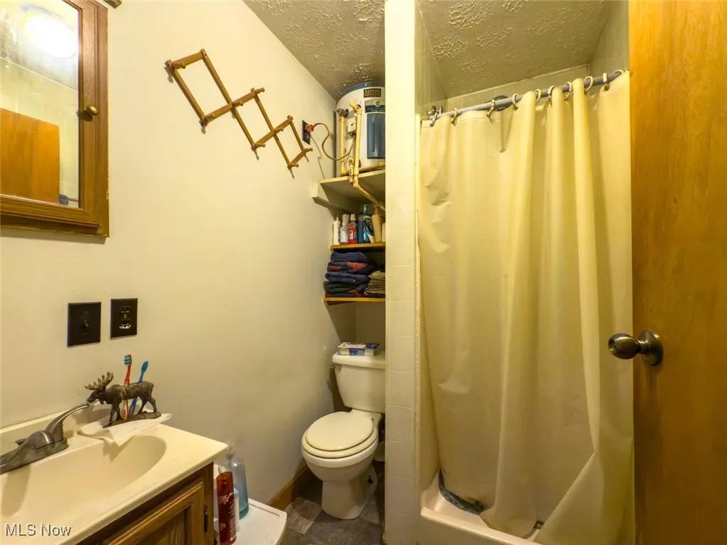 Full bath featuring a textured ceiling, vanity, and a shower with curtain