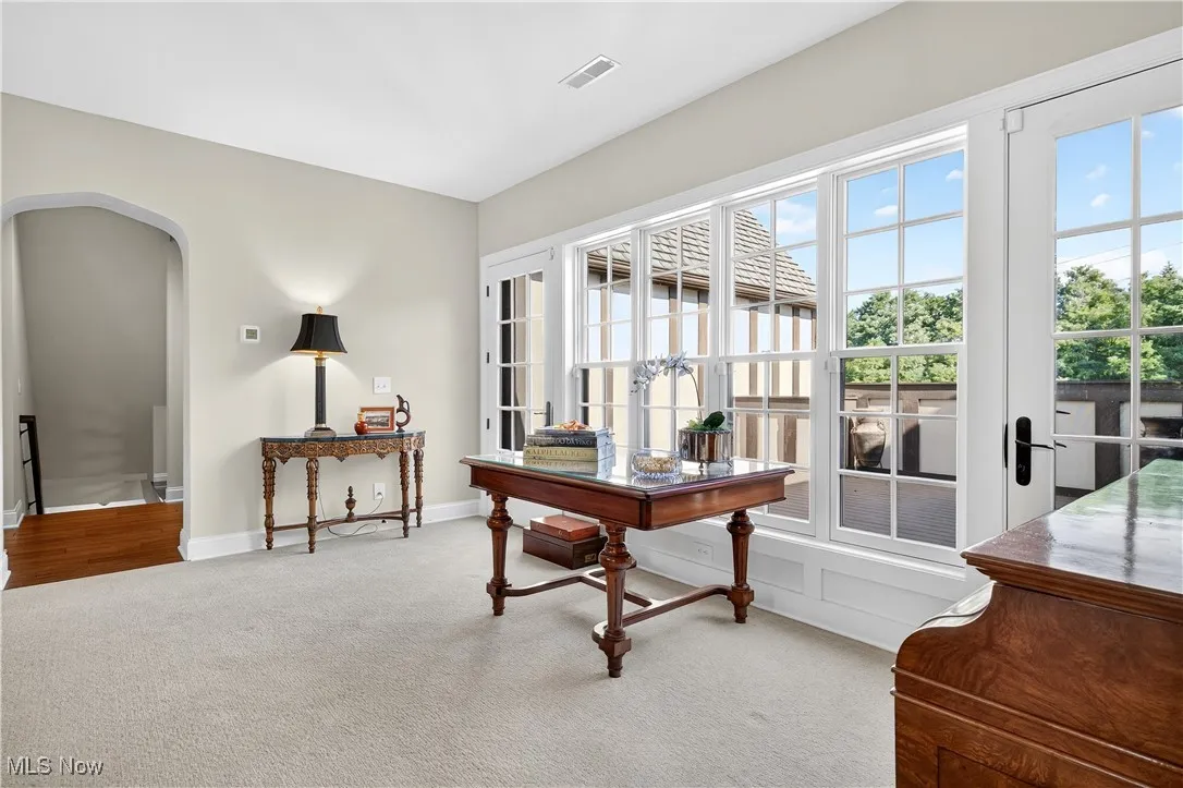 Carpeted home office featuring arched walkways and baseboards