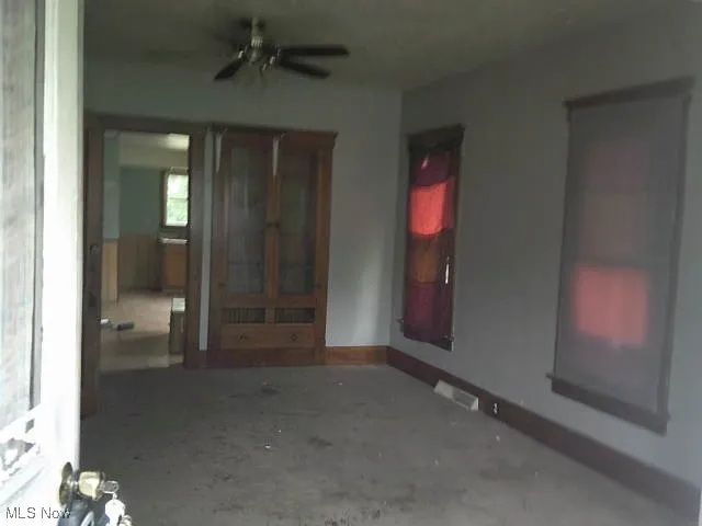 Empty room featuring ceiling fan and unfinished concrete floors