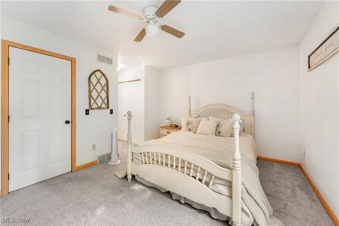 Carpeted bedroom featuring ceiling fan and a closet