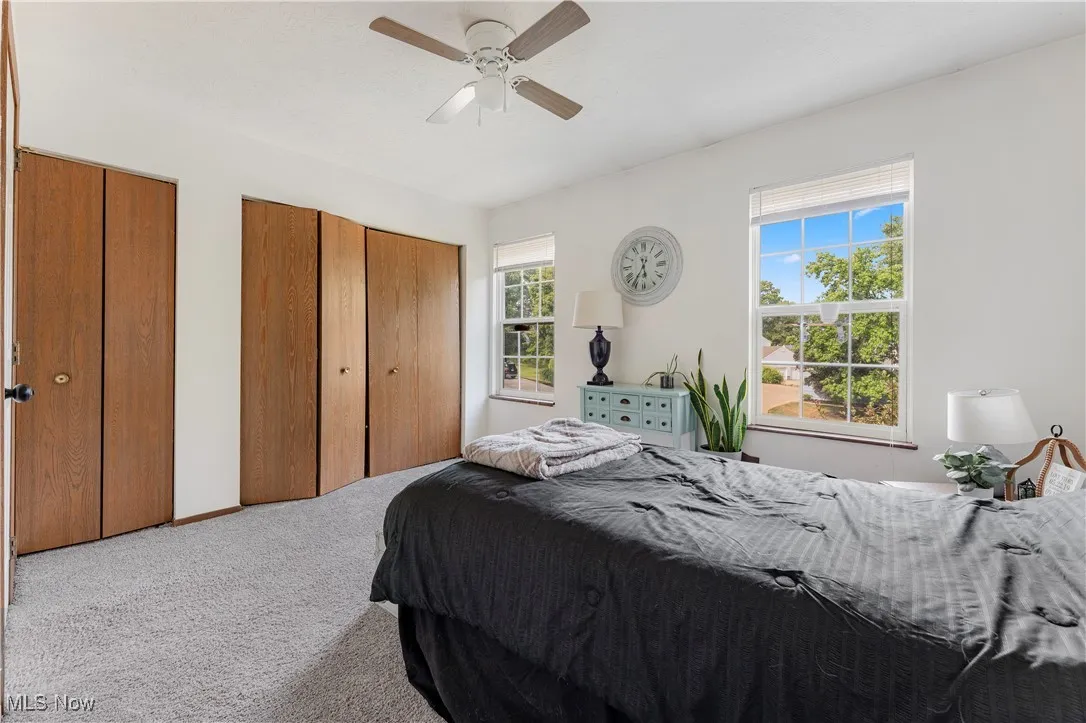 Bedroom with carpet, multiple closets, and ceiling fan