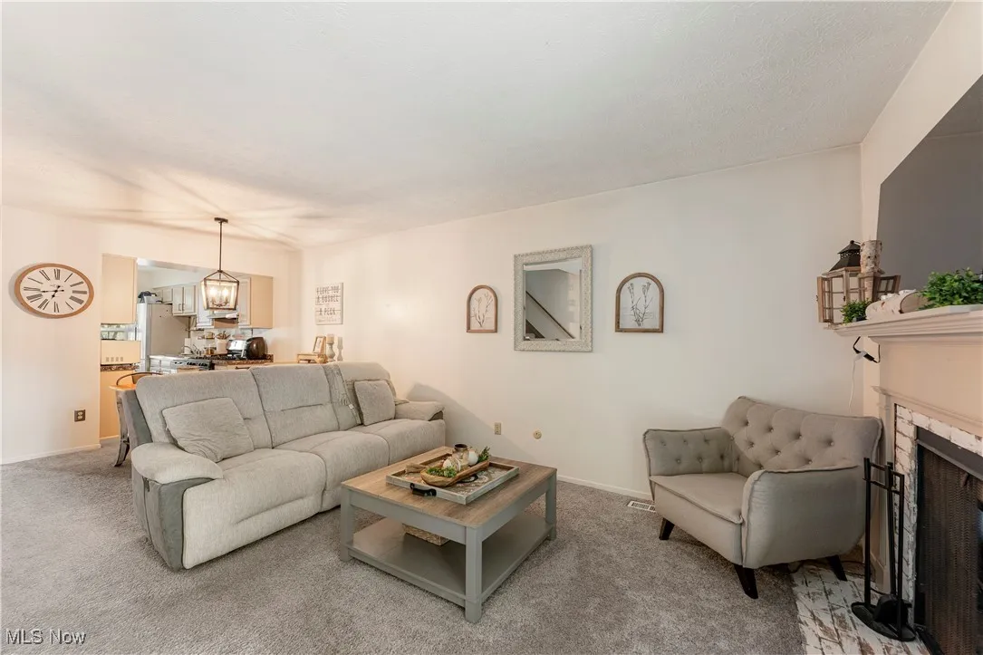 Living area featuring light colored carpet, a fireplace, and a chandelier