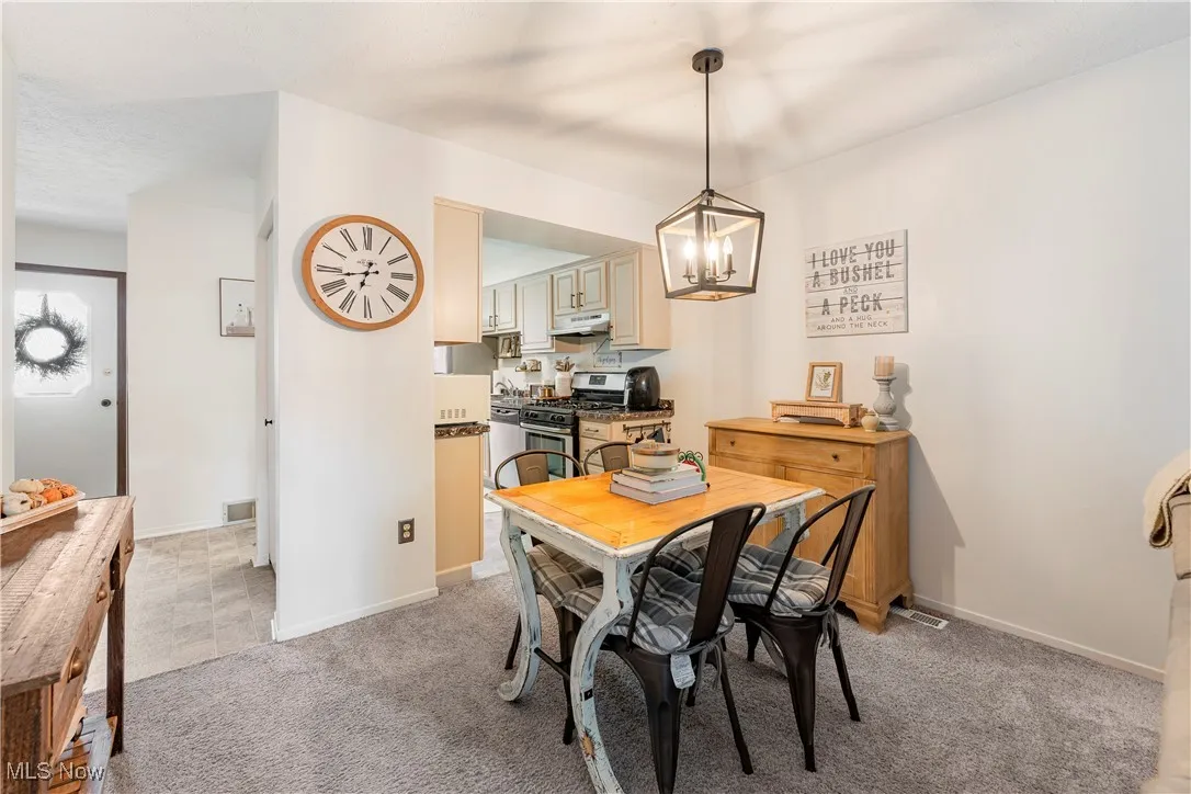 Dining space with light carpet and a chandelier