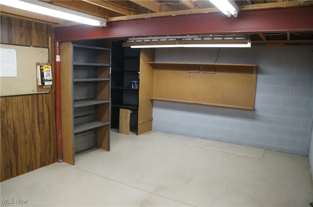 Unfinished basement featuring wooden walls and wainscoting