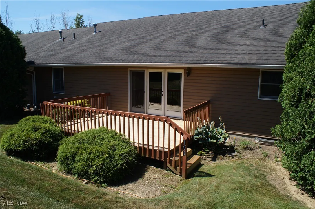 Rear view of house featuring a deck, roof with shingles, and a yard