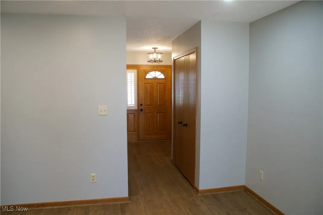 Foyer entrance with wood finished floors, a textured ceiling, and a chandelier