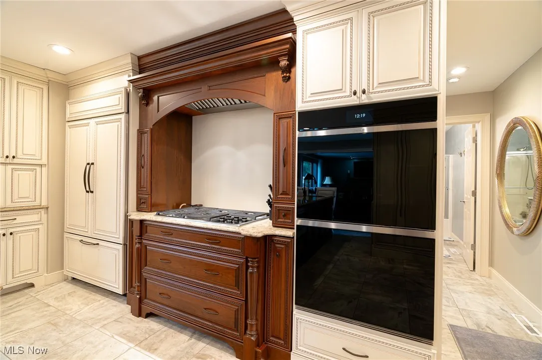 Kitchen with cream cabinets, recessed lighting, paneled refrigerator, quartz counters, and stainless steel gas cooktop