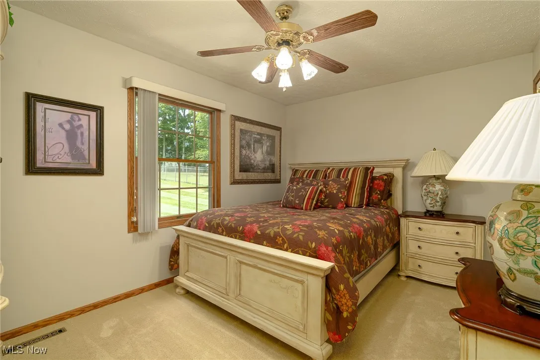 Bedroom with light colored carpet, a ceiling fan.