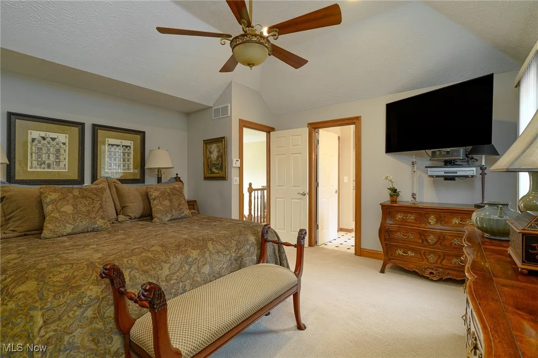 Bedroom with light colored carpet, a vaulted ceiling, and a ceiling fan