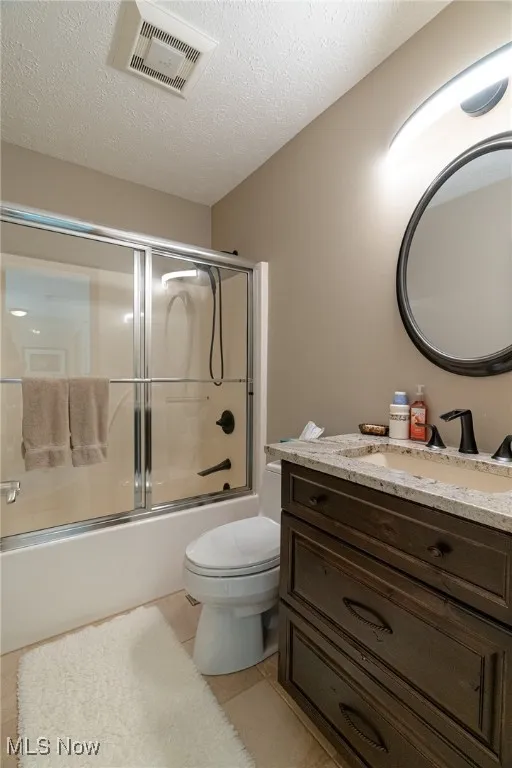 Bathroom with a custom vanity, tile patterned floors, and shower / bath combination with glass door