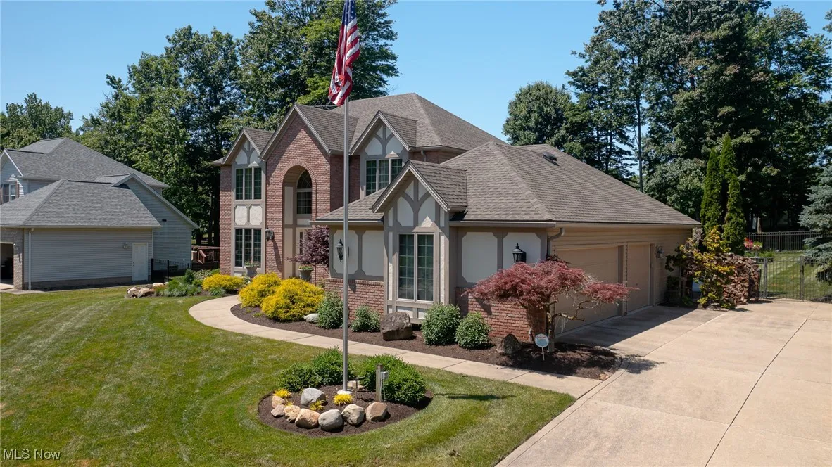 English style home with brick siding, a 3 car side load garage, roof with shingles, driveway, and stucco siding