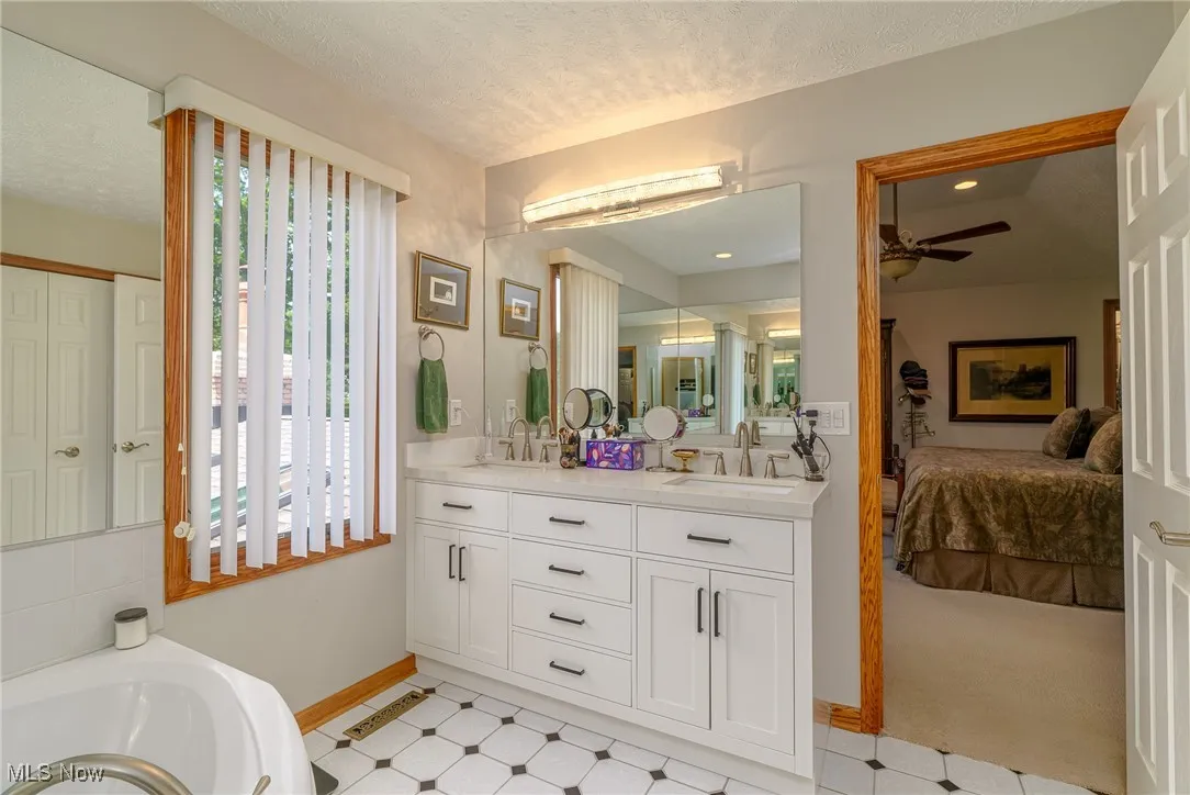 Full bath with double vanity, connected bathroom, a bath.