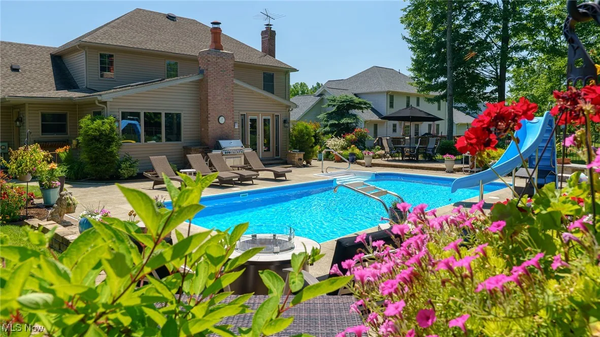 Outdoor pool with a patio area, a water slide.