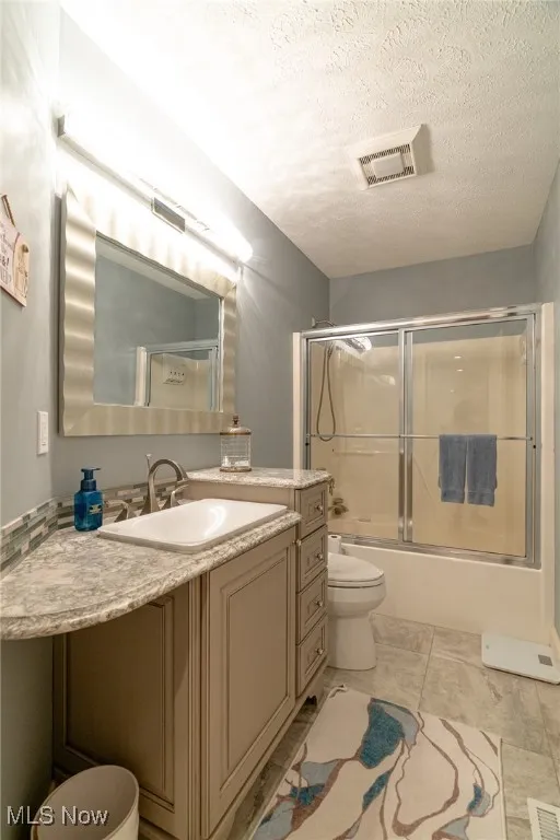 Full bathroom featuring a vanity, bath / shower combo with glass door, and tile floors