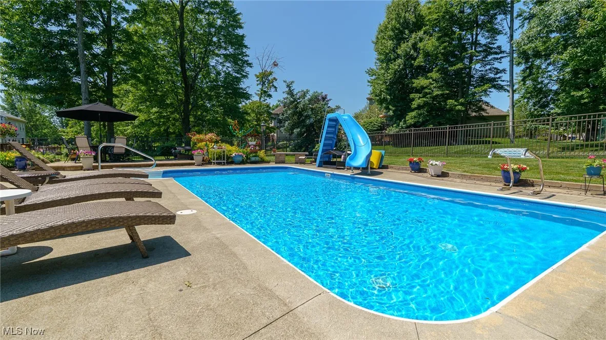 View of pool with a water slide and a patio area