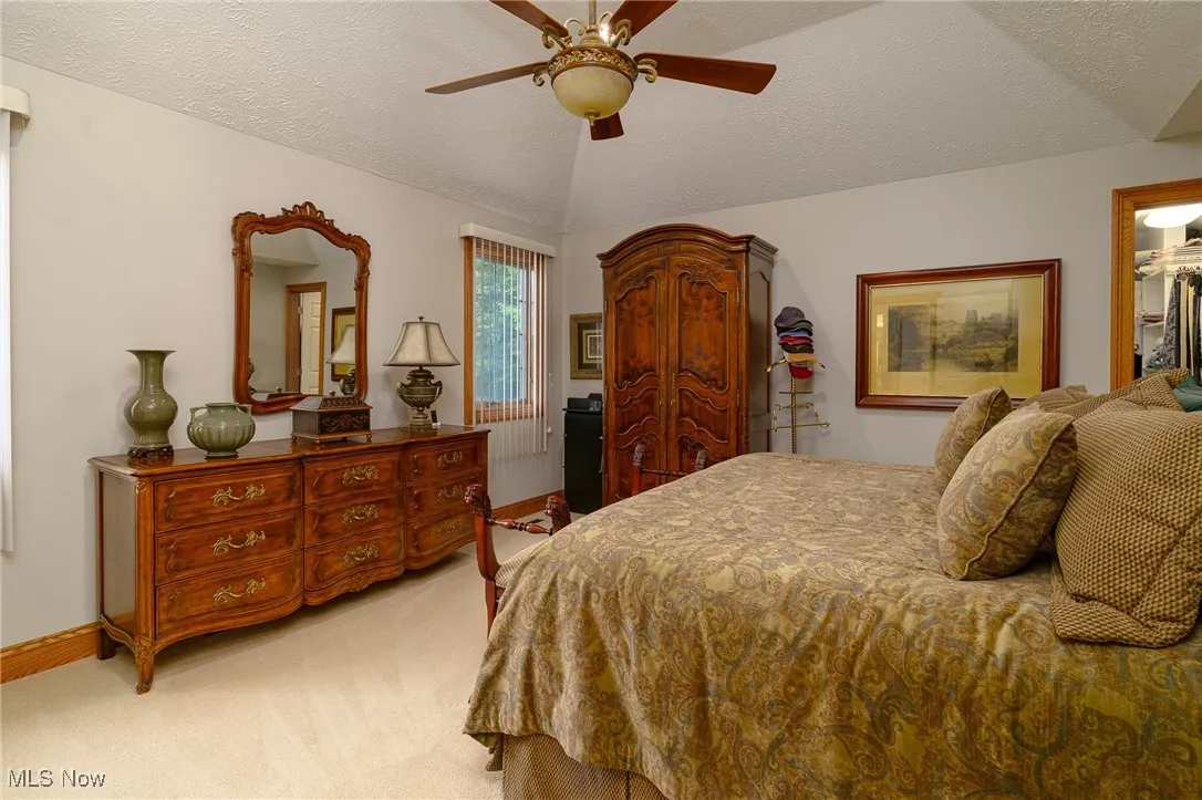 Bedroom with light colored carpet, ceiling fan, and a spacious closet