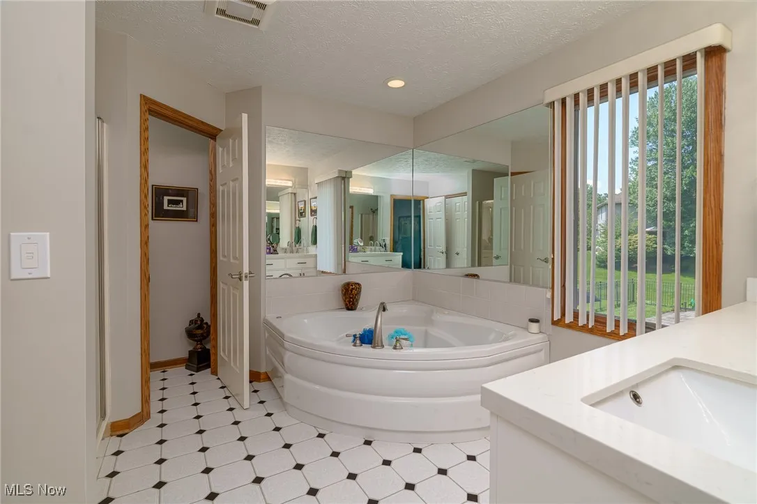 Bathroom featuring vanity, a bath, and tile patterned floors