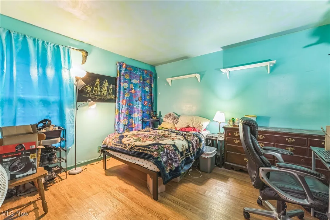 Bedroom with wood finished floors and a desk