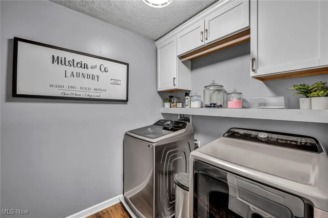 Laundry room featuring cabinet space, separate washer and dryer, a textured ceiling, and wood finished floors located on 2nd floor