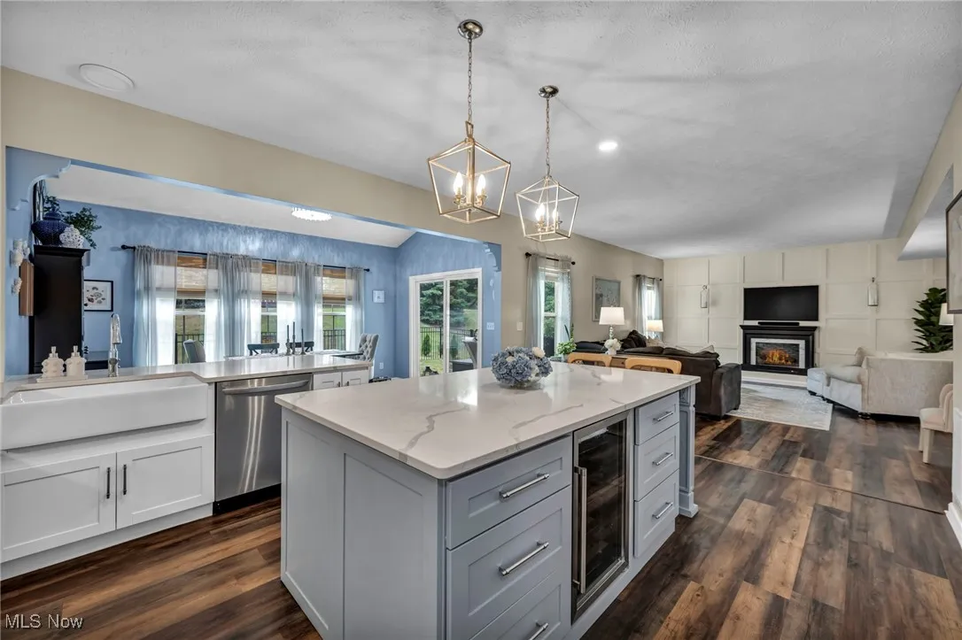 Kitchen featuring gray cabinetry, wine cooler, open floor plan, stainless steel dishwasher, and a chandelier