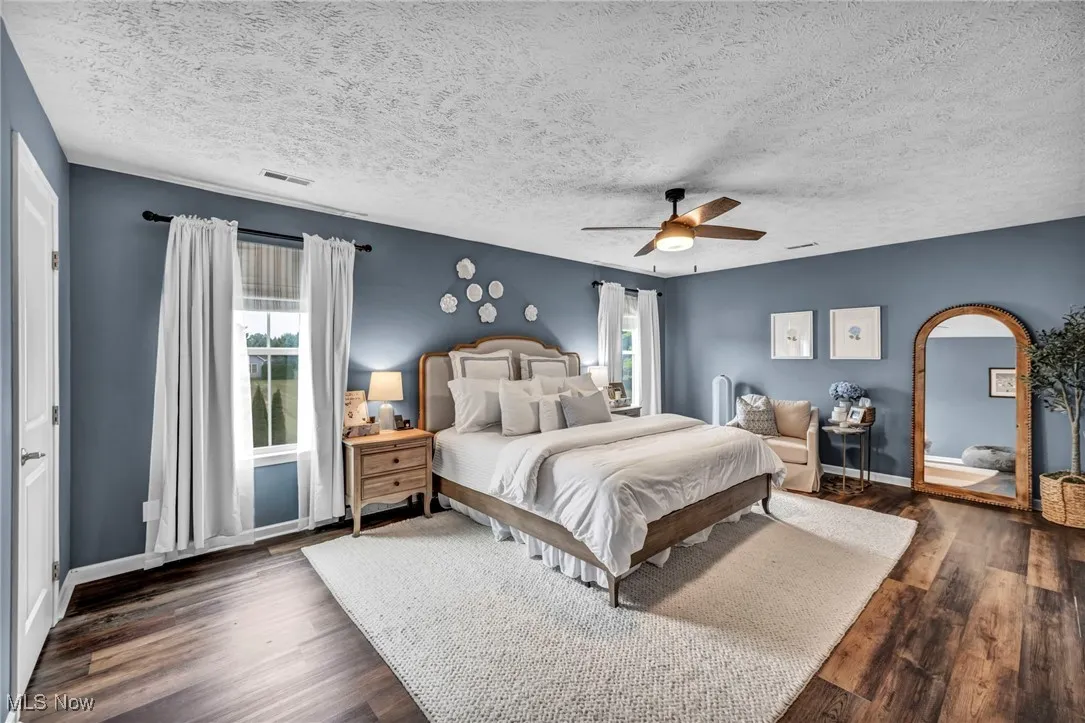 Primary Bedroom with a ceiling fan, wood finished floors, and a textured ceiling walk in closet and in suite bath