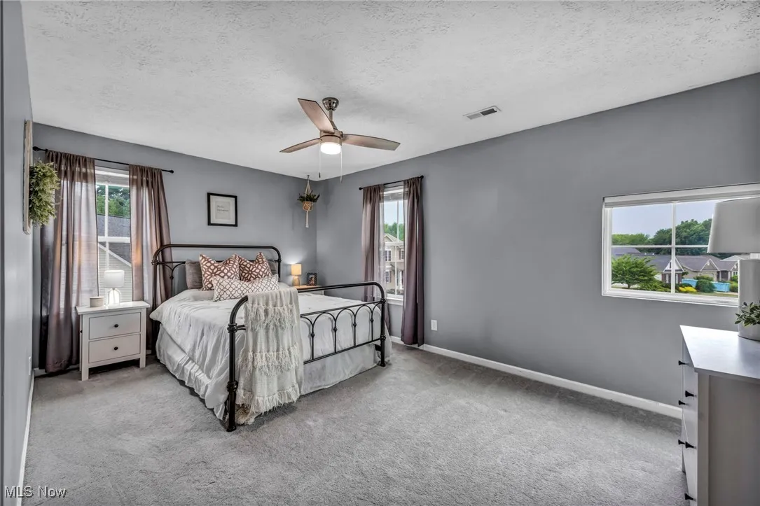 Bedroom 2 featuring multiple windows, a textured ceiling, carpet floors, and ceiling fan