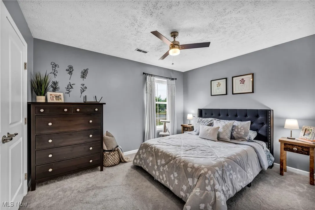 Bedroom 1 with carpet, a textured ceiling, and a ceiling fan