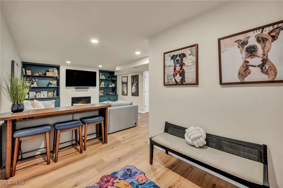  featuring a glass covered fireplace, light wood-style flooring, recessed lighting, and built in shelves