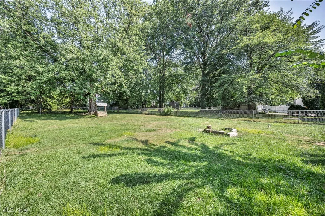 Fenced backyard with view of wooded area