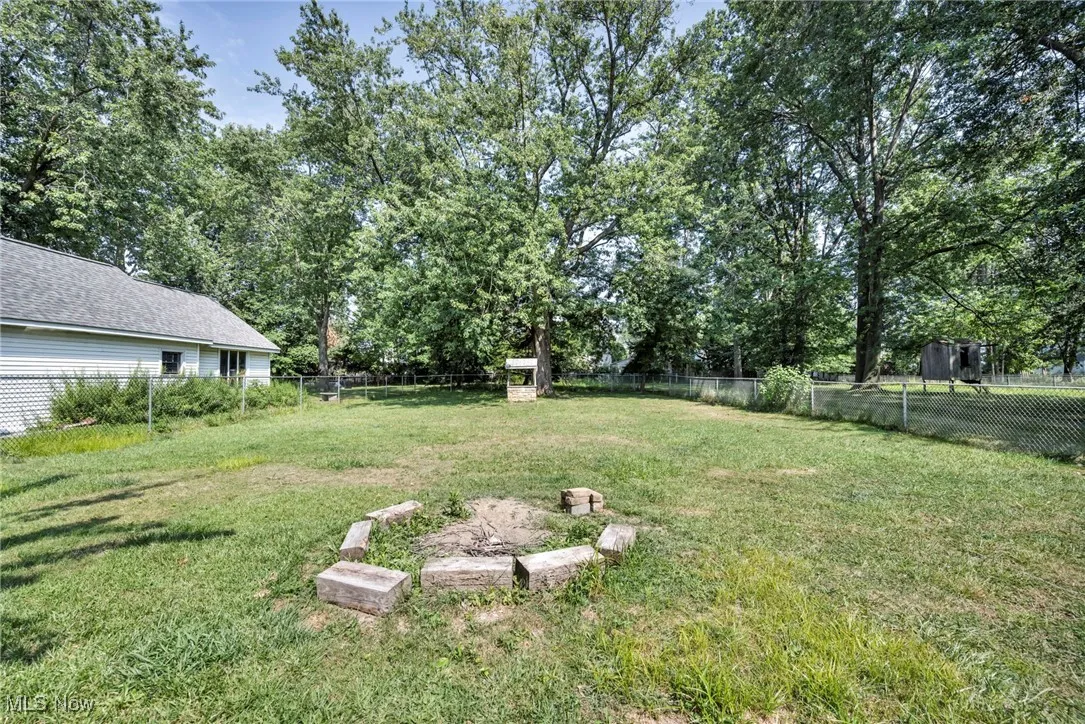 Fenced backyard featuring view of scattered trees