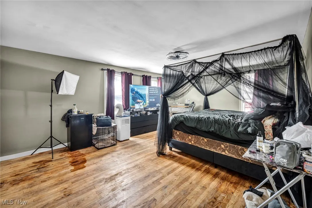 Bedroom featuring wood finished floors and freestanding refrigerator