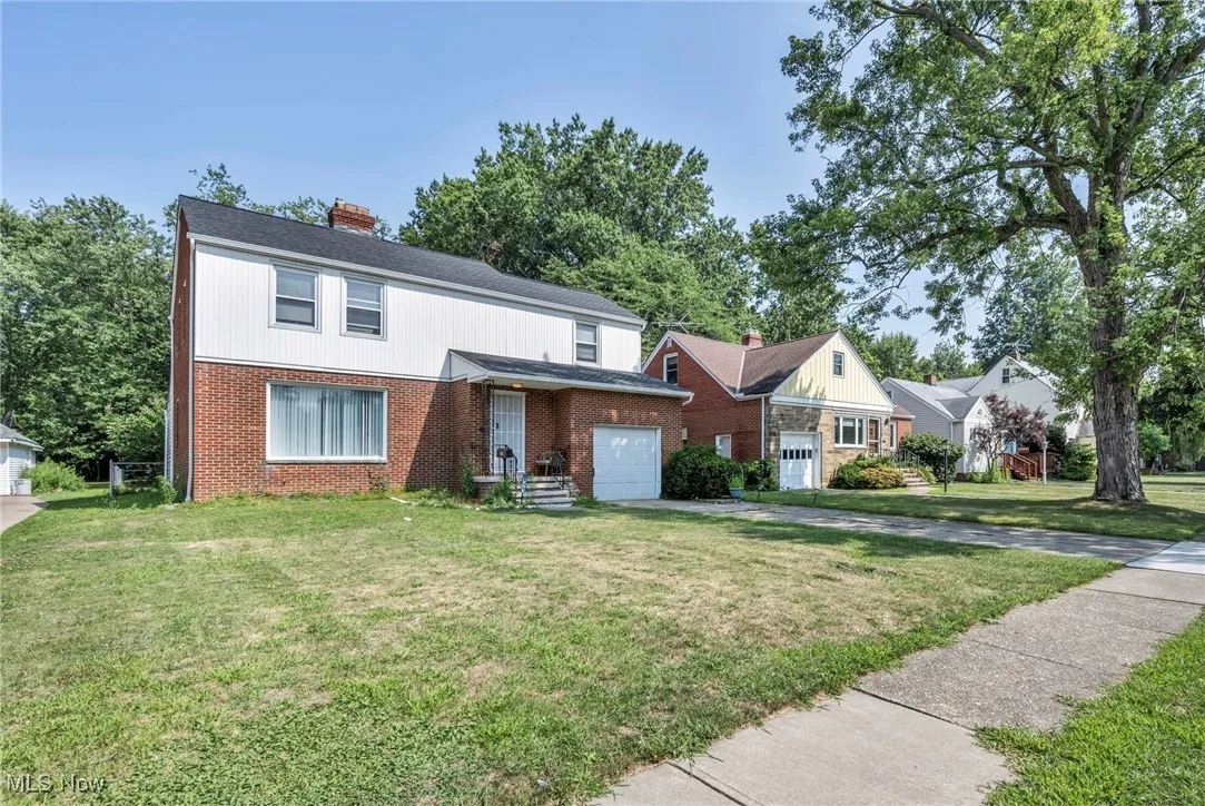 Traditional-style home featuring concrete driveway, brick siding, a front yard, and a chimney