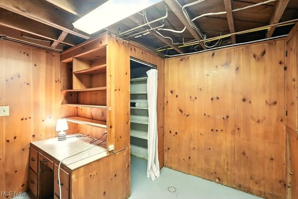 Below grade pantry/desk and work area featuring wooden walls