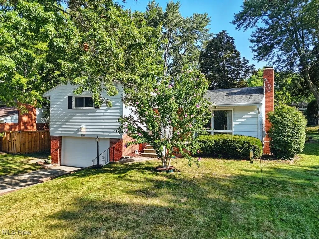 View of front of house with a garage, a chimney, a front lawn, and brick siding