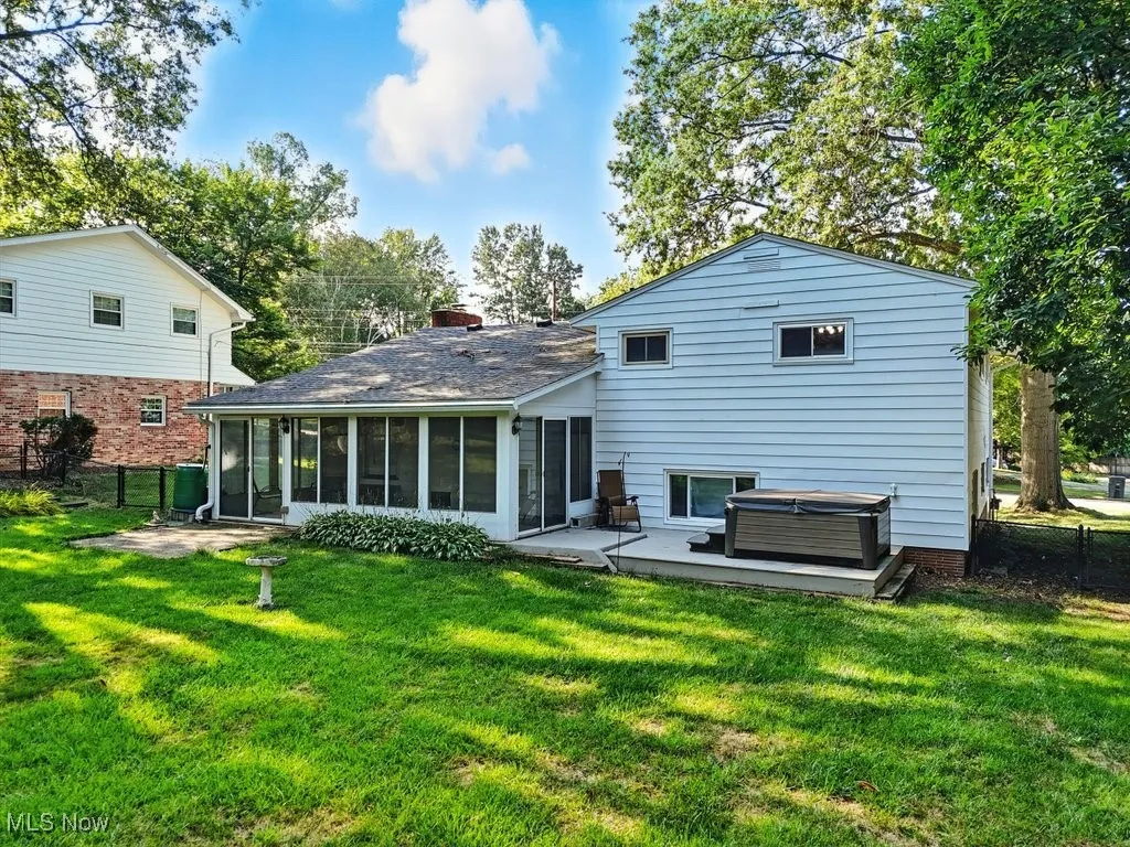 Rear view of property with a hot tub, a sunroom, and a patio