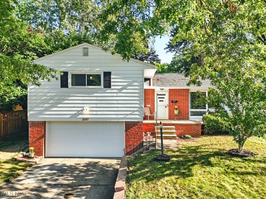 Split level home with brick siding, a garage, a front yard, and driveway