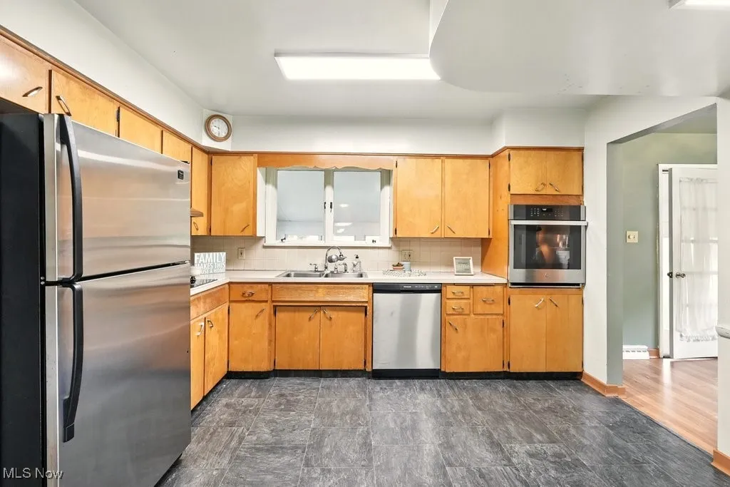 Kitchen has linoleum floors, wood cabinets and a window looking into the back yard
