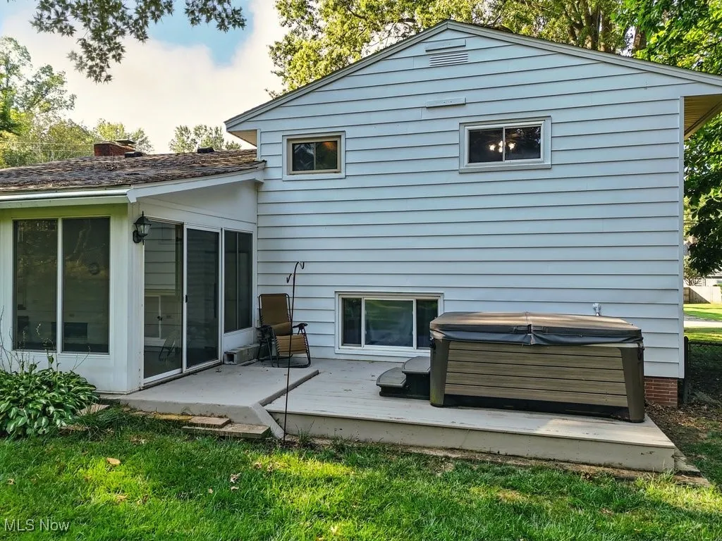 Rear view of property featuring a deck, a yard, and a hot tub