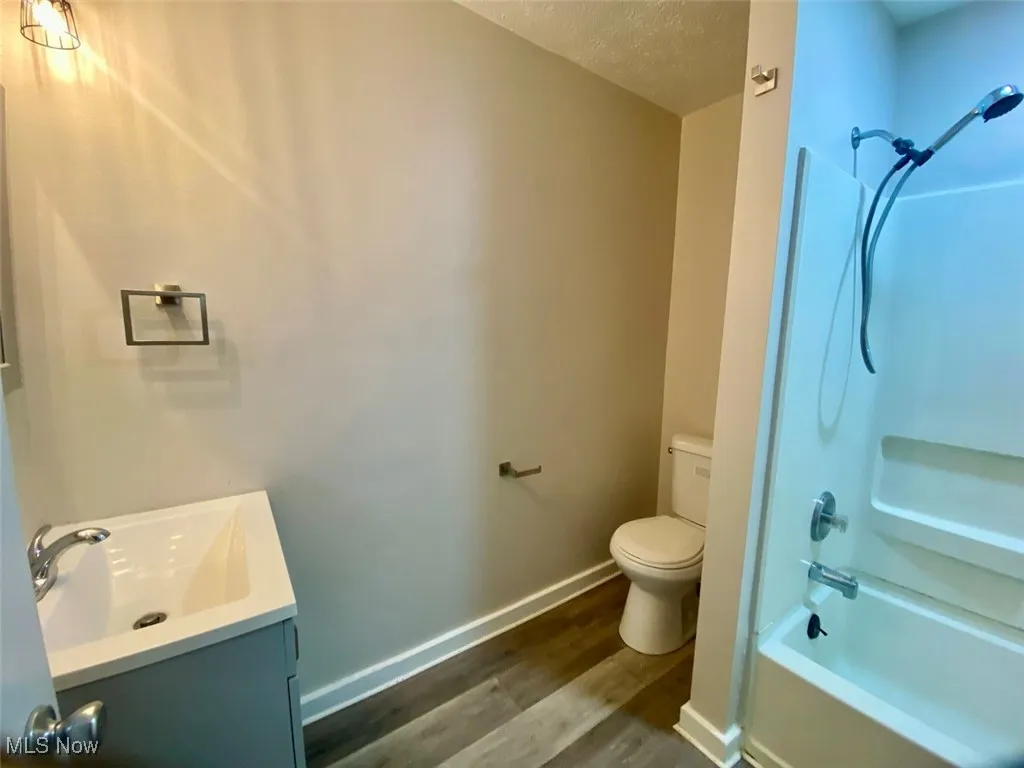 Bathroom featuring tub / shower combination, vanity, wood finished floors, and a textured ceiling