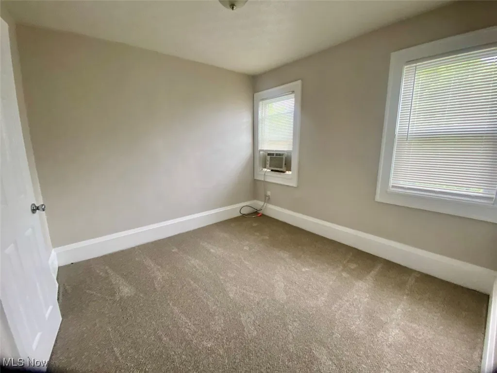 Carpeted spare room featuring healthy amount of natural light and cooling unit