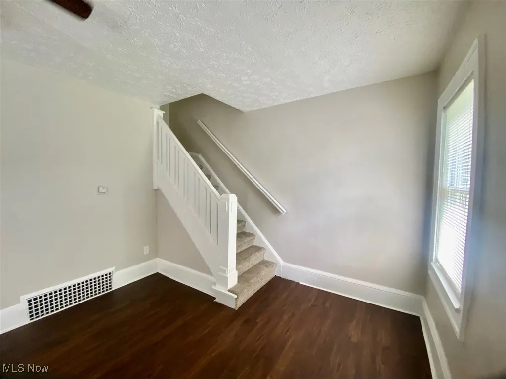 Stairs with wood finished floors and a textured ceiling