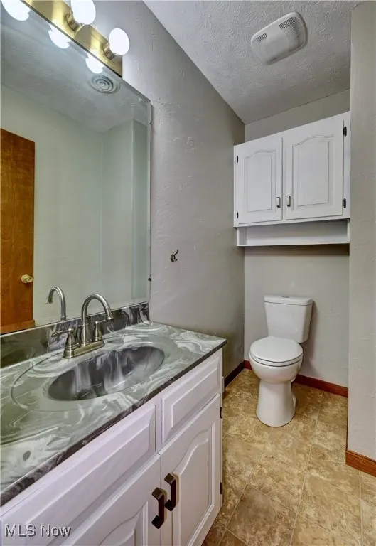 Bathroom with a textured wall, a textured ceiling, vanity, and tile patterned flooring