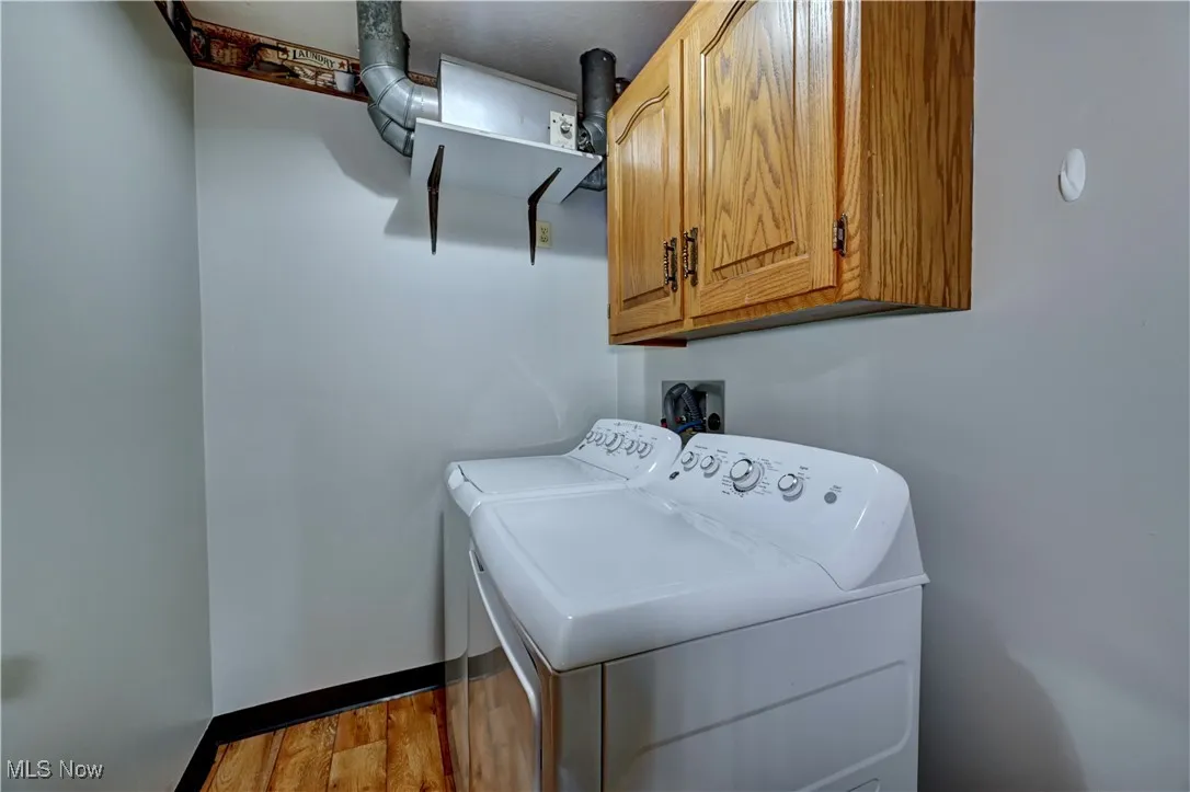 Laundry room featuring washing machine and dryer, cabinet space, and dark wood-style floors