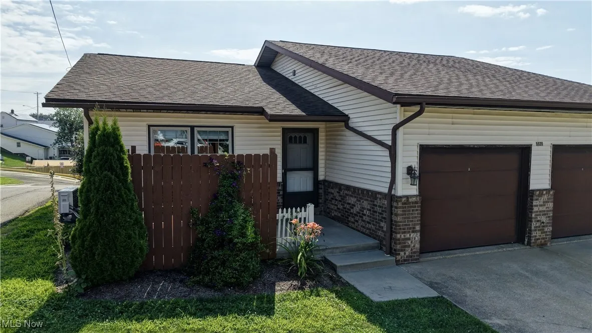 View of front of home with roof with shingles, a garage, concrete driveway, and brick siding