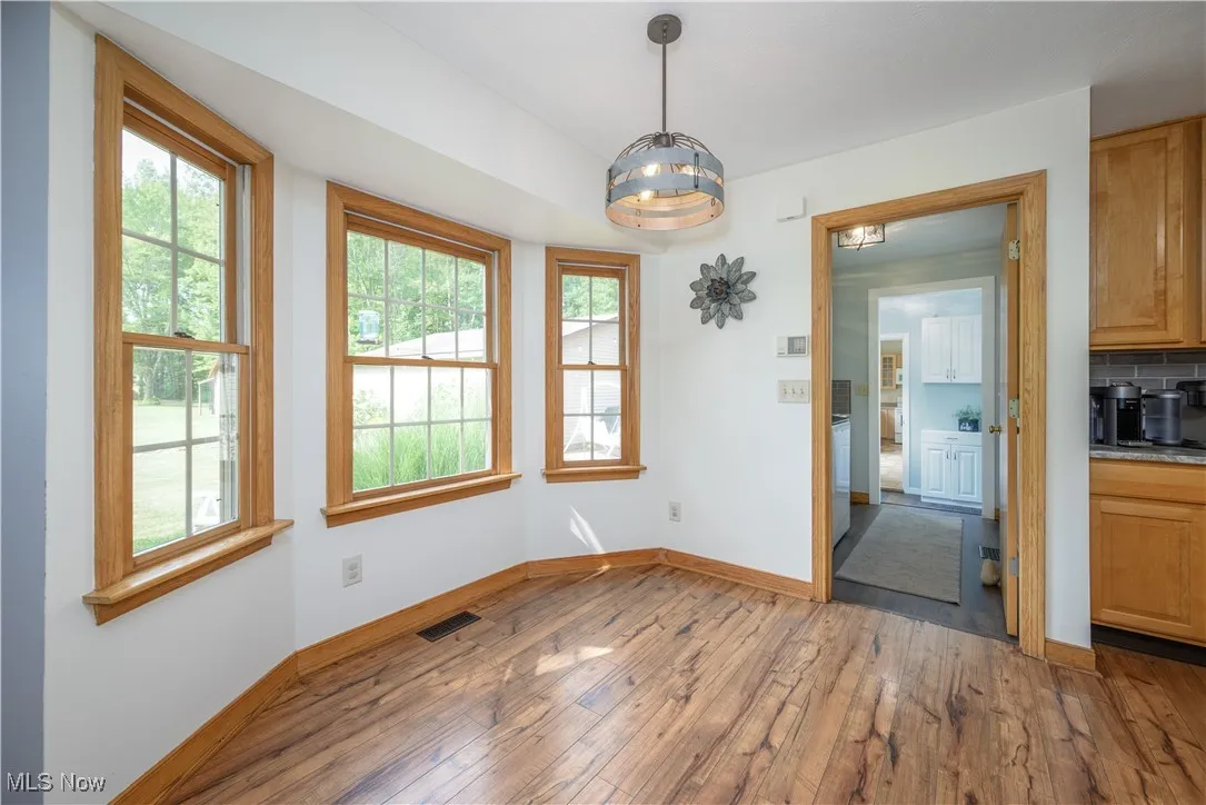 Unfurnished dining area with hardwood / wood-style flooring and baseboards