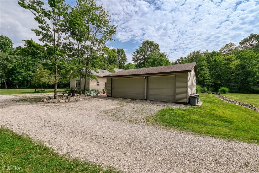 Ranch-style home with a garage, a front lawn, and an outbuilding