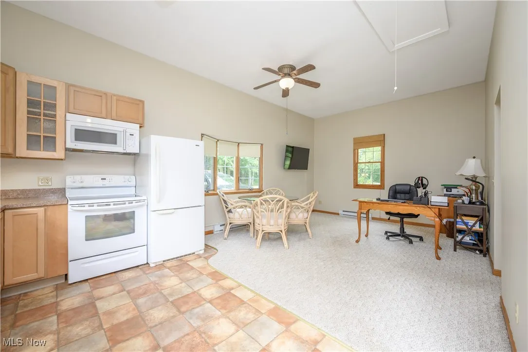Kitchen with white appliances, plenty of natural light, glass insert cabinets, and light brown cabinets