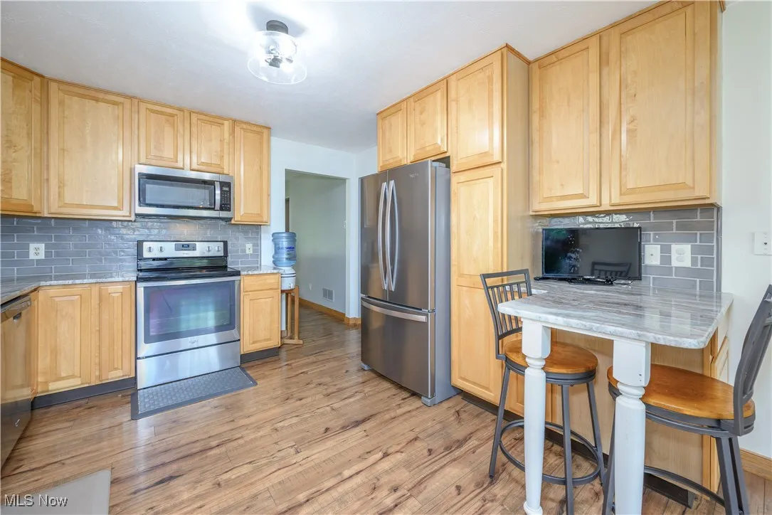Kitchen with tasteful backsplash and light brown cabinets