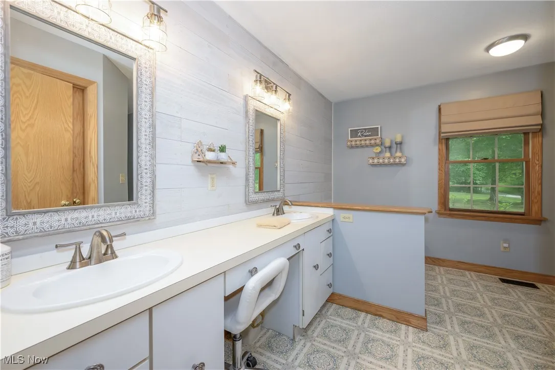 Bathroom featuring double vanity, wood walls, and tile patterned floors